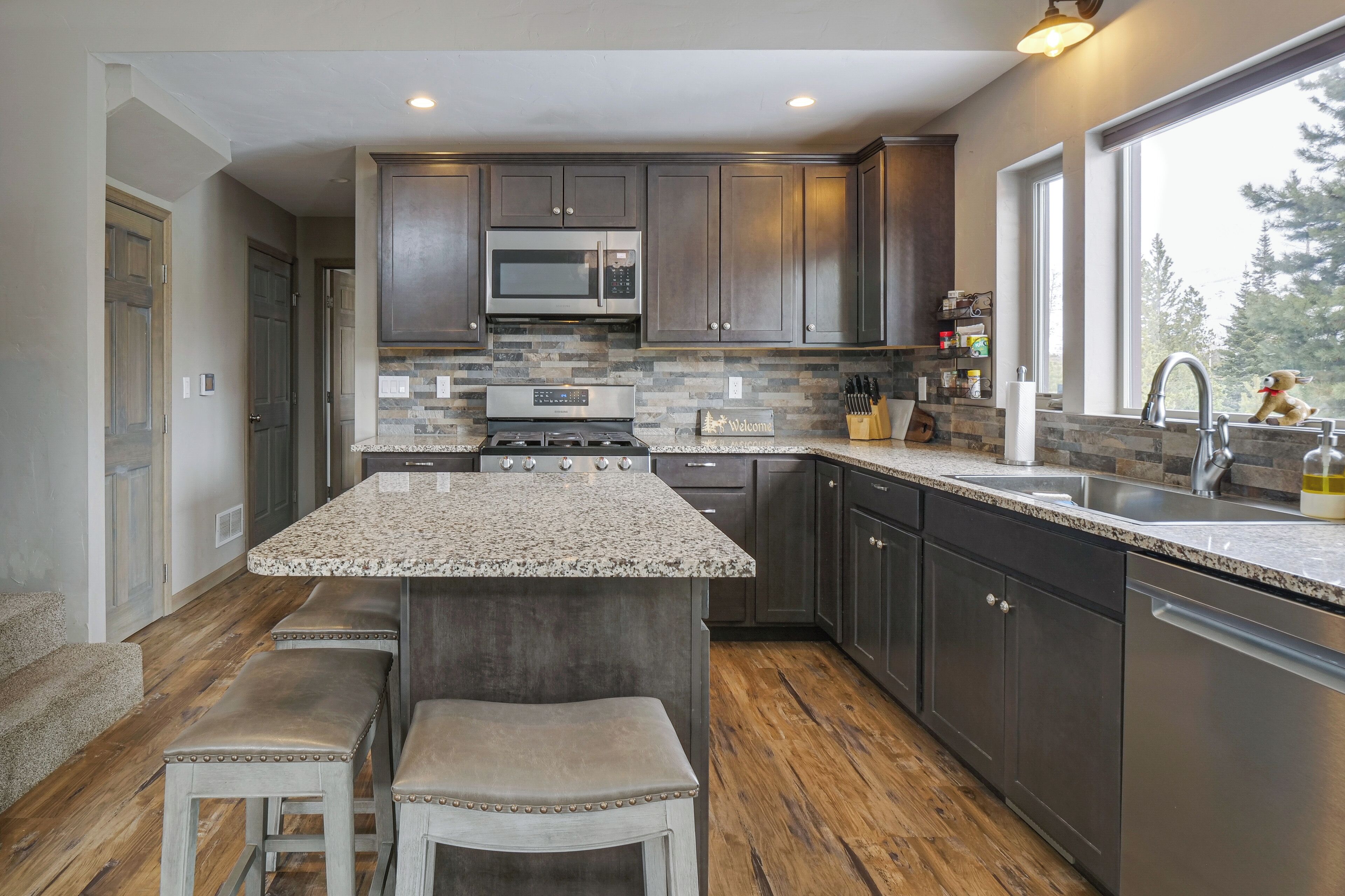 A modern kitchen with granite countertops, stainless steel appliances, and dark wood cabinets.