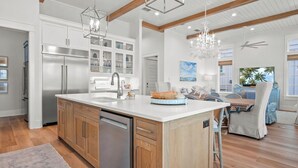 A modern kitchen with a central island, stainless steel appliances, and wooden cabinetry. - Premier Lakefront Beach Home@Cinnamon Shore South By Luxe Pools & Amenities (Port Aransas)