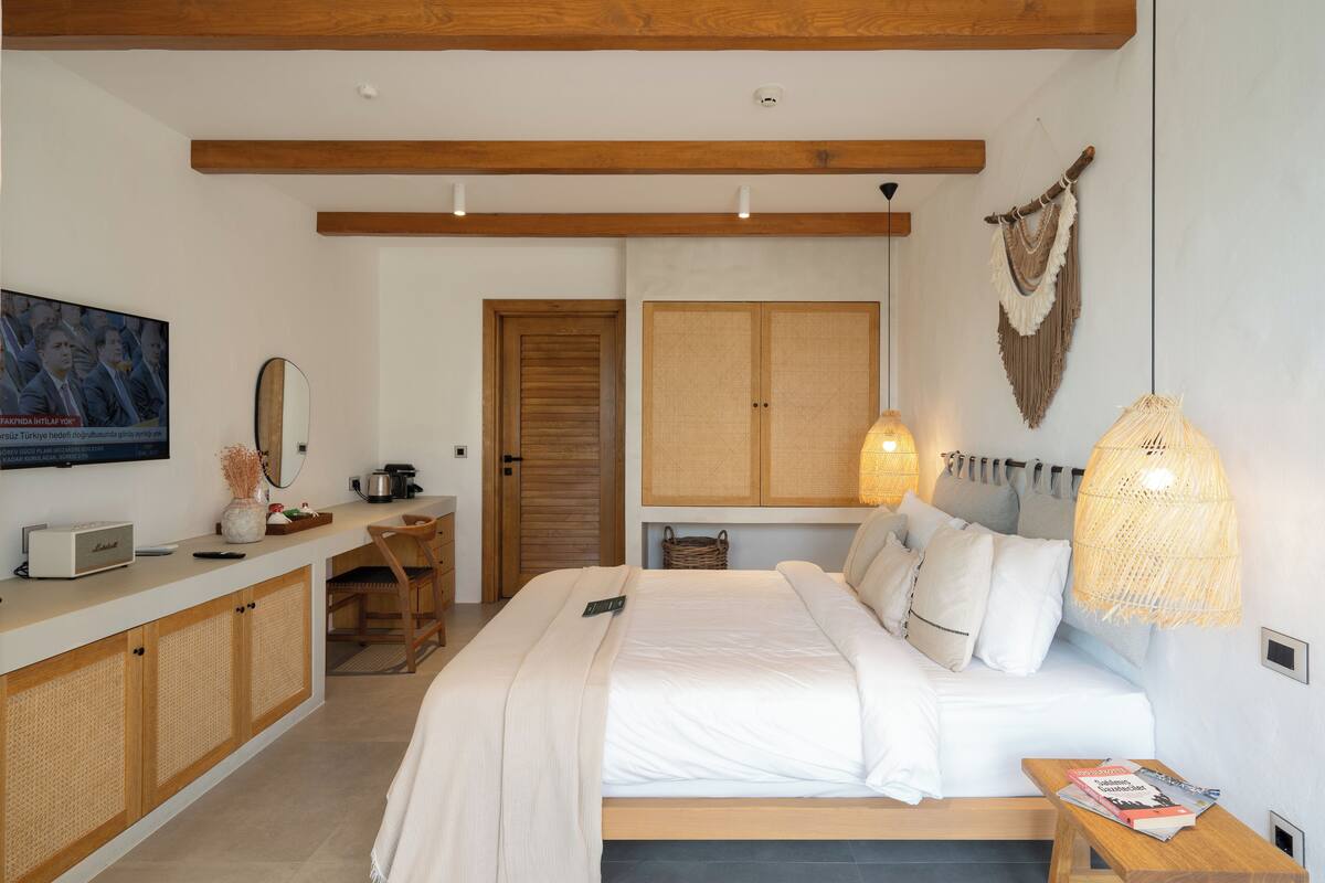 A bedroom with a bed, bedside table, wooden wardrobe, and a television on the wall.