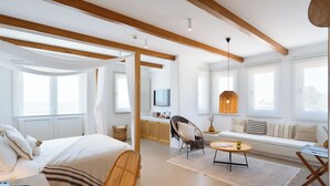 Una habitación de hotel moderna con cama, sofá, mesa de comedor y televisor.