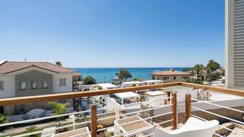 A balcony with a view of the sea, white buildings, and a clear sky.