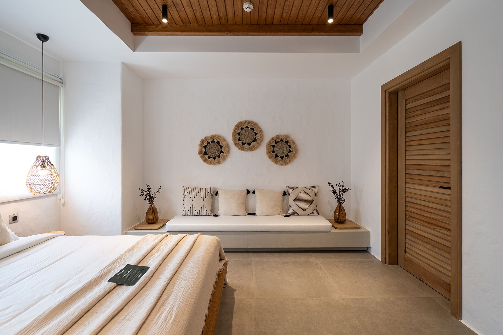 Un dormitorio con cama, una banca y decoración en la pared.