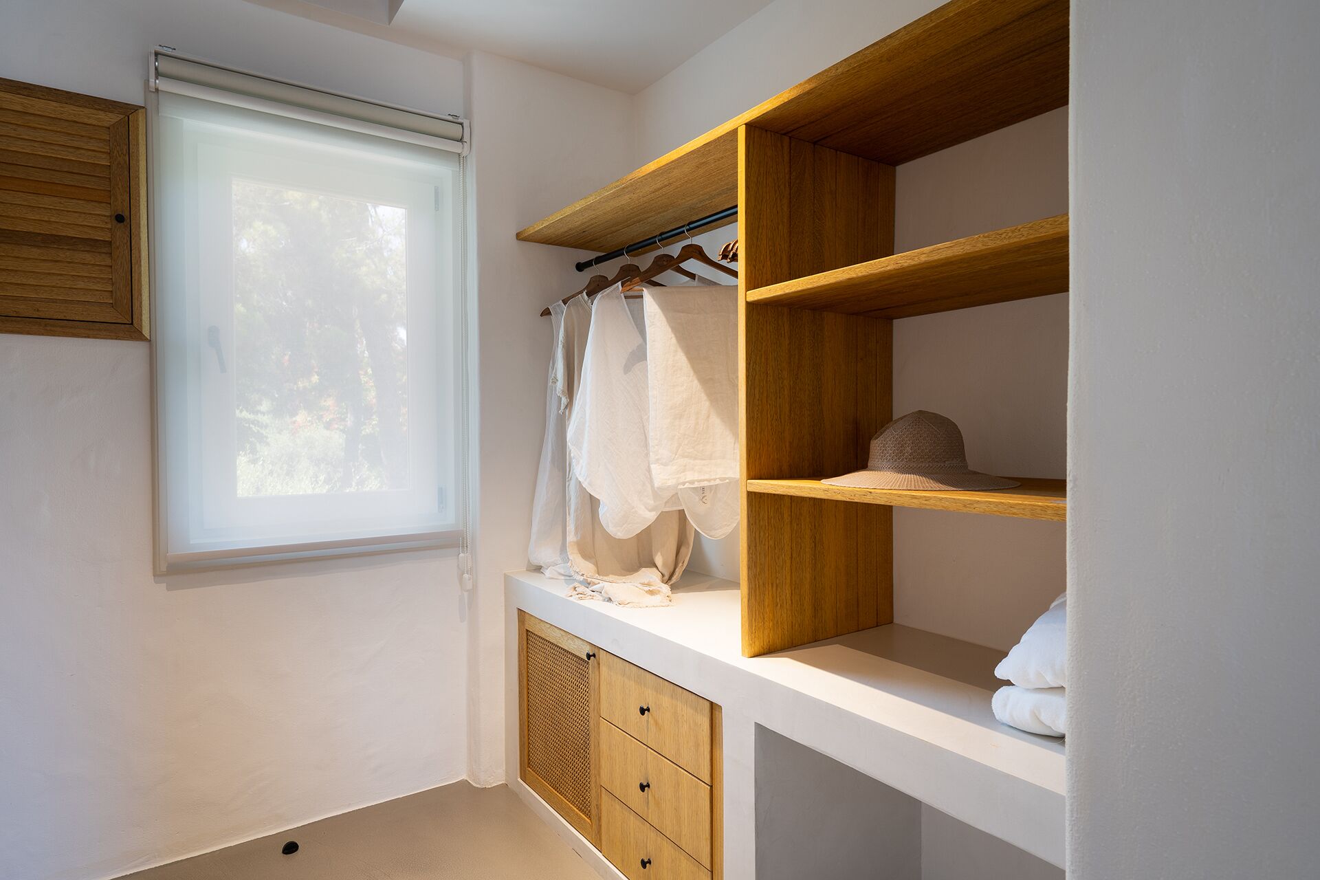 Une salle de bain avec une fenêtre, des étagères en bois et un porte-serviettes.