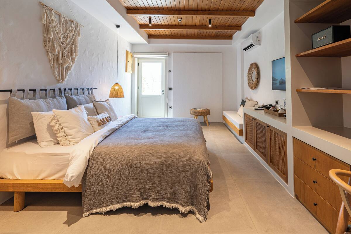 A modern bedroom with a wooden bed, a macrame wall hanging, and a minimalist design.