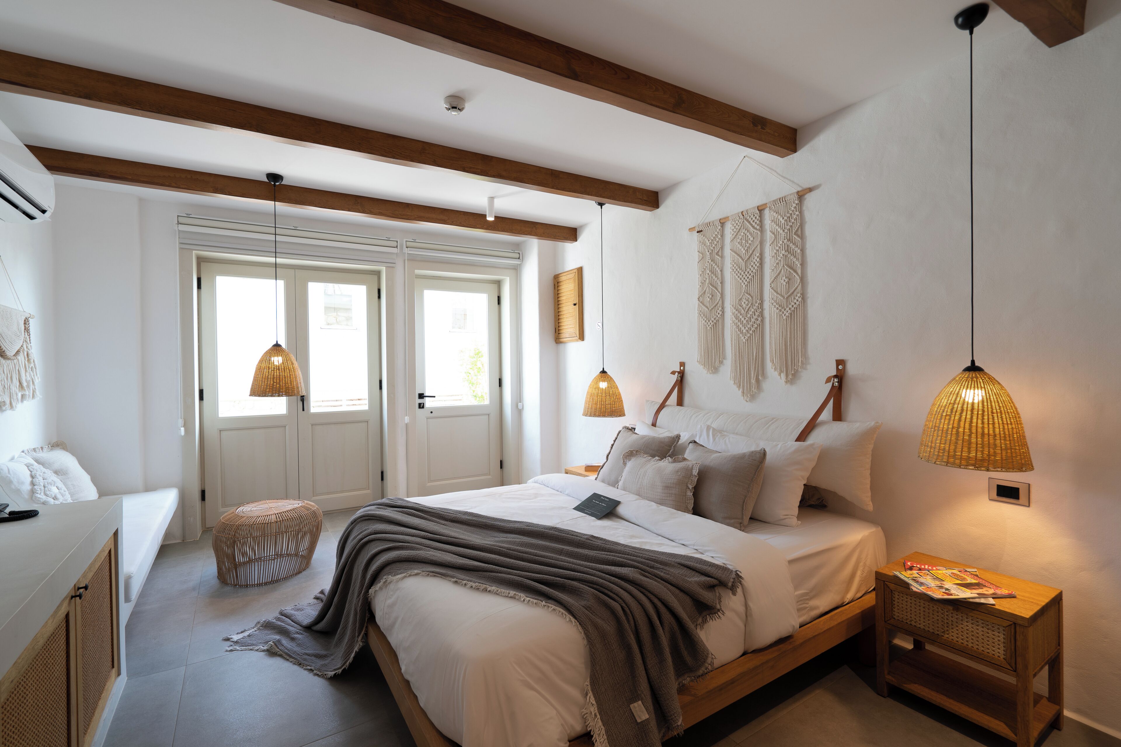 A bedroom with a bed, bedside lamps, a bedside table, and a window.