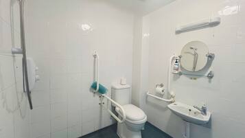A bathroom with a toilet, sink, shower, and grab bars.