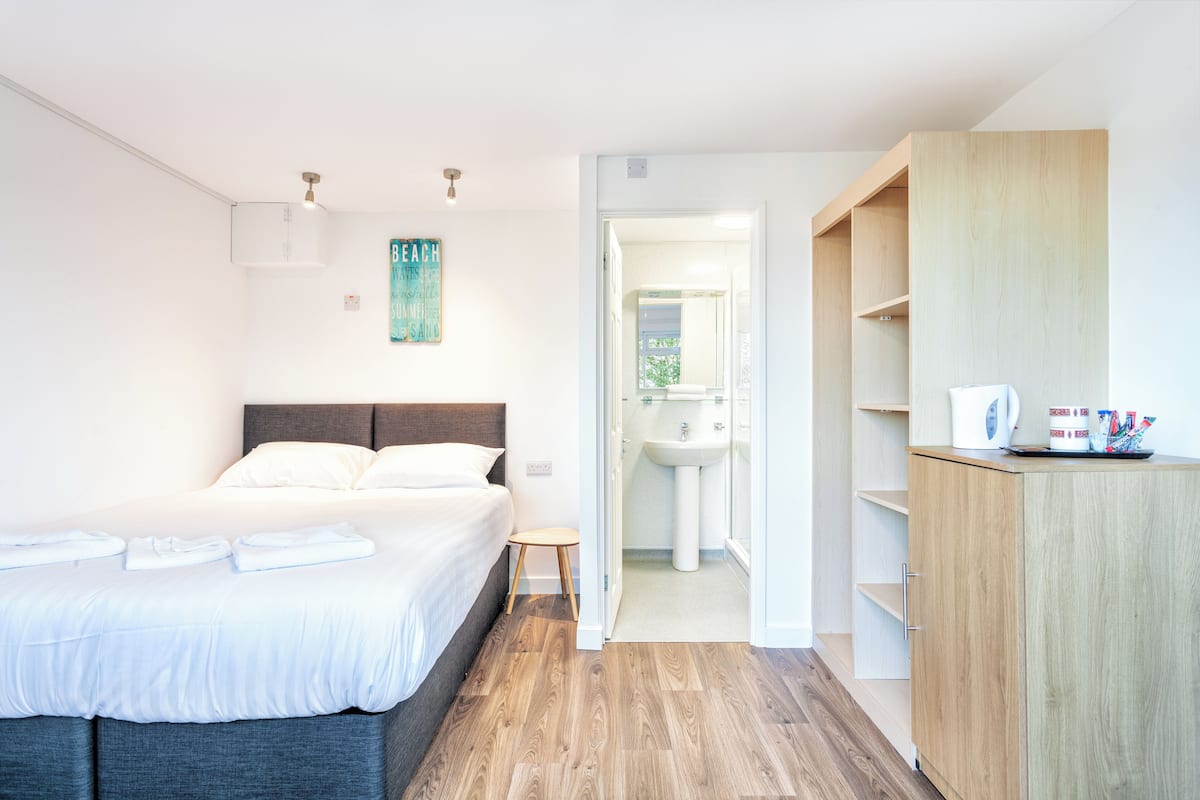 Een slaapkamer met een bed, nachtkastje en een houten kledingkast.