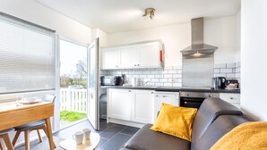 A modern kitchen with white cabinets, a stainless steel range hood, and a black countertop. - North Devon Resort (Ilfracombe)