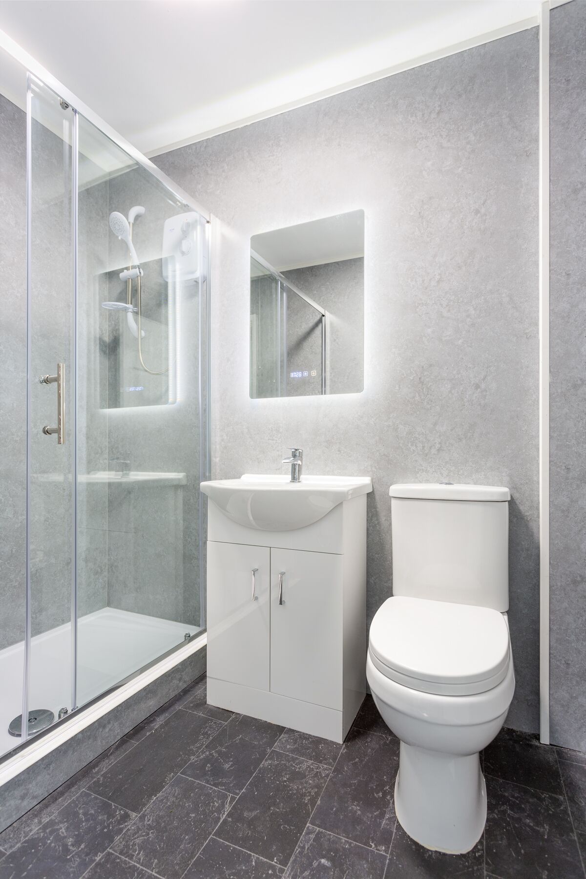 Un baño moderno con ducha de vidrio, lavamanos blanco y retrete.