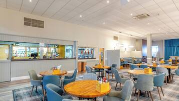 A hotel lobby with multiple seating areas, a bar, and a counter with various items.