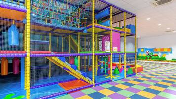 A multi-level indoor play area with netted structures and colorful flooring.