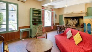 Une pièce chaleureuse avec un canapé rouge, une table en bois et une bibliothèque verte.