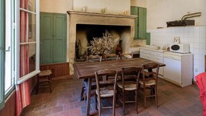 Une cuisine traditionnelle avec une cheminée, une table à manger en bois et des armoires vertes.