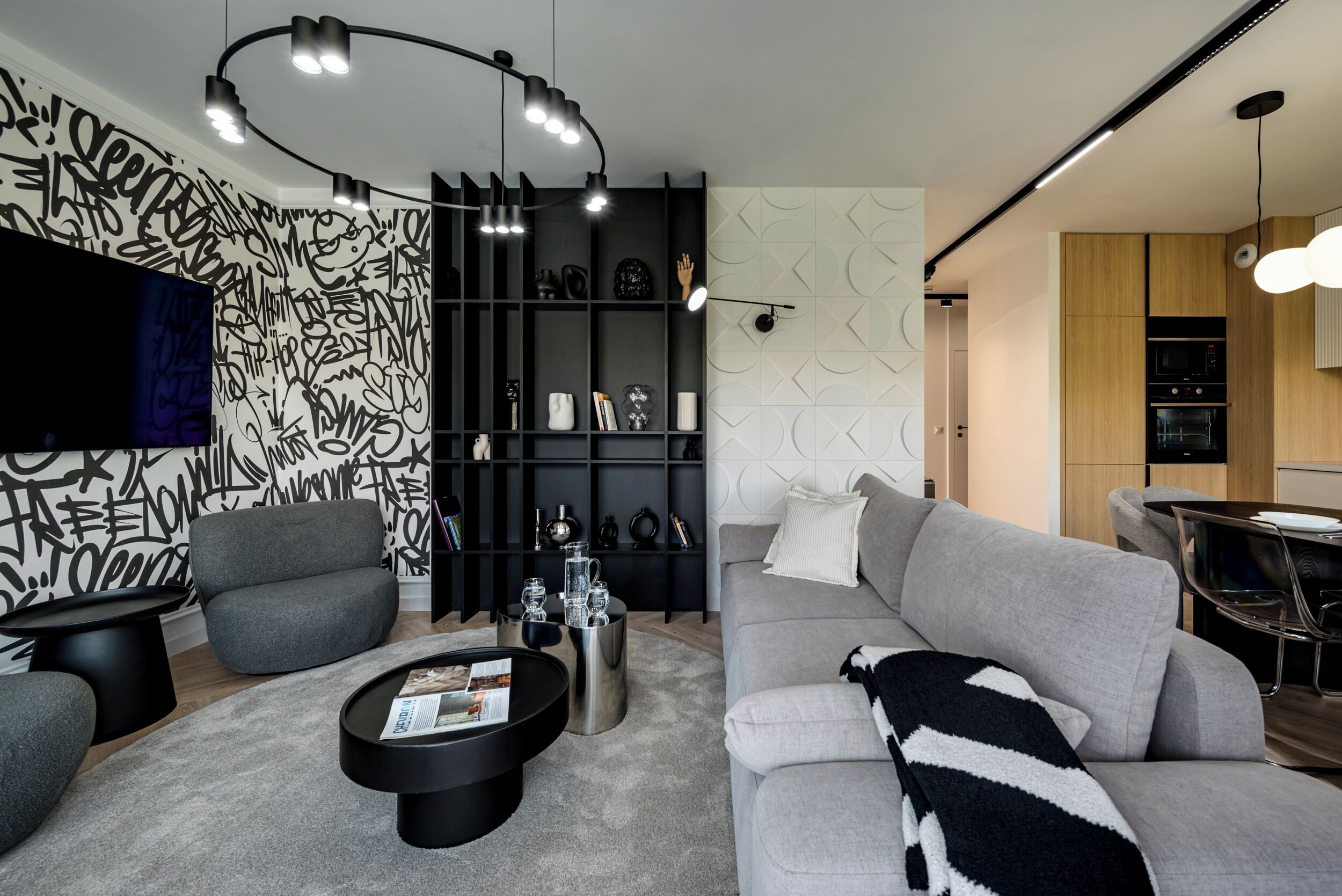 Una sala moderna con un sofá gris, una mesa de centro negra y una estantería negra.