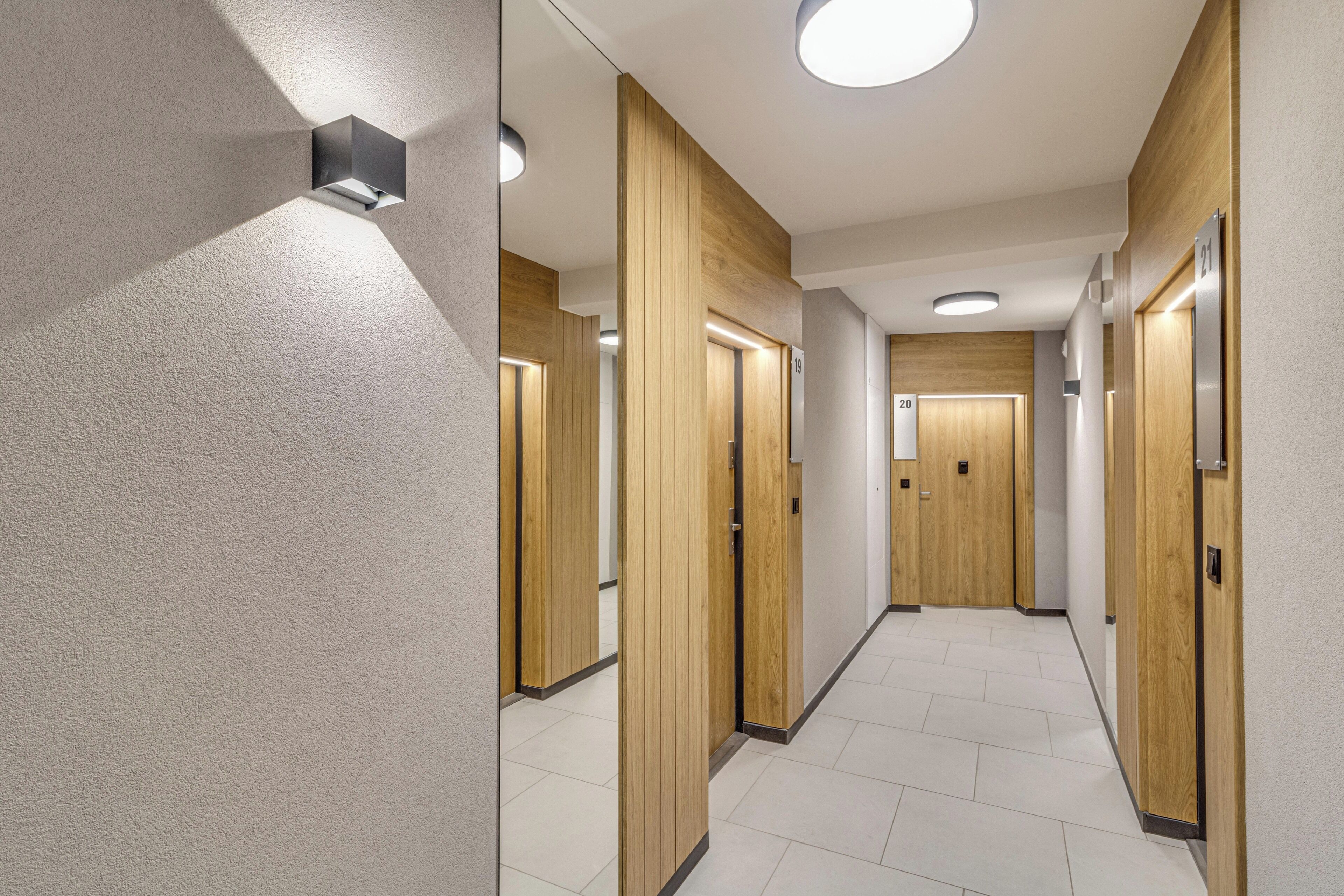 Un pasillo moderno con puertas de madera, numeradas para las habitaciones, e iluminación en el techo.