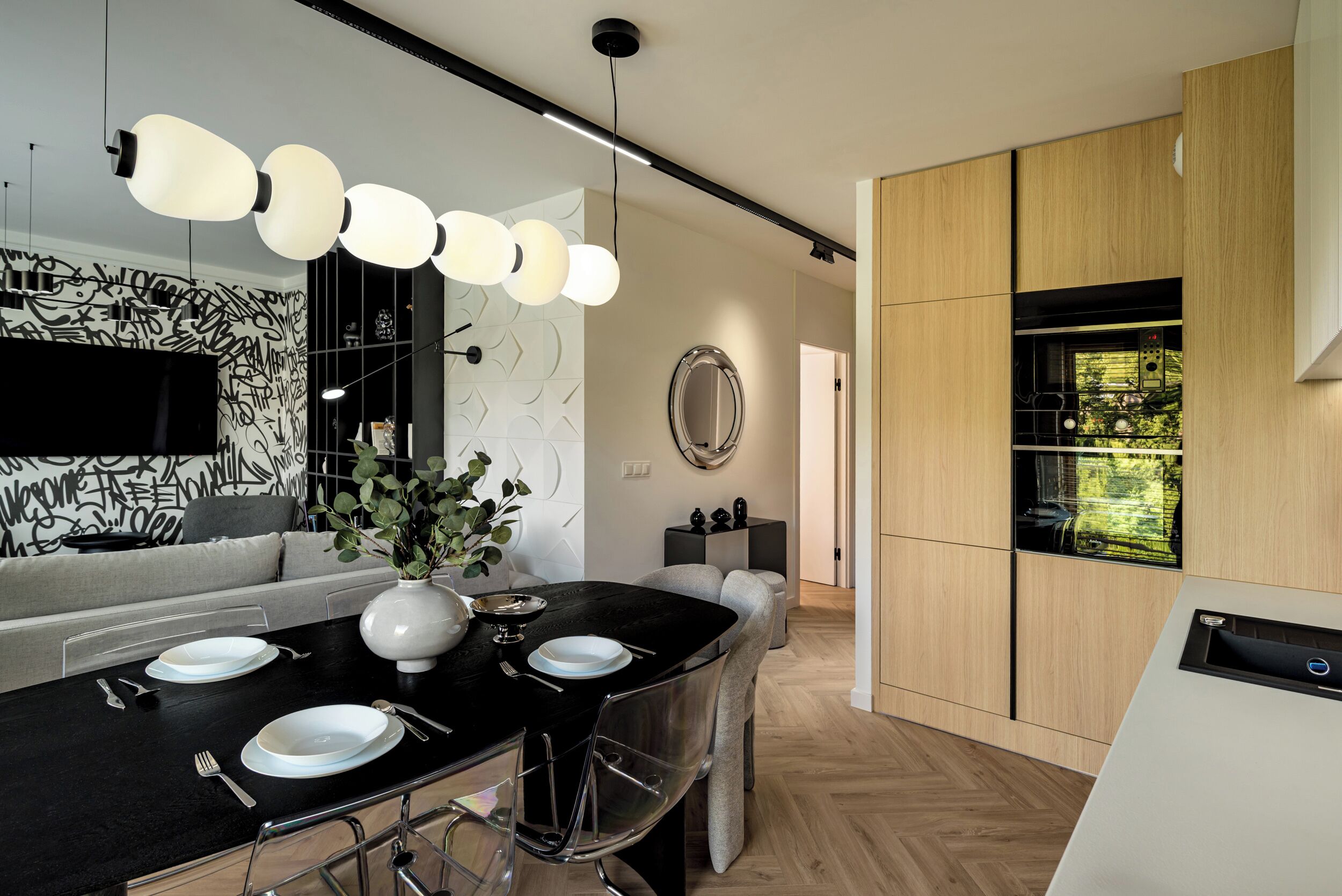A modern kitchen with a black countertop, white plates, and a vase of green plants.