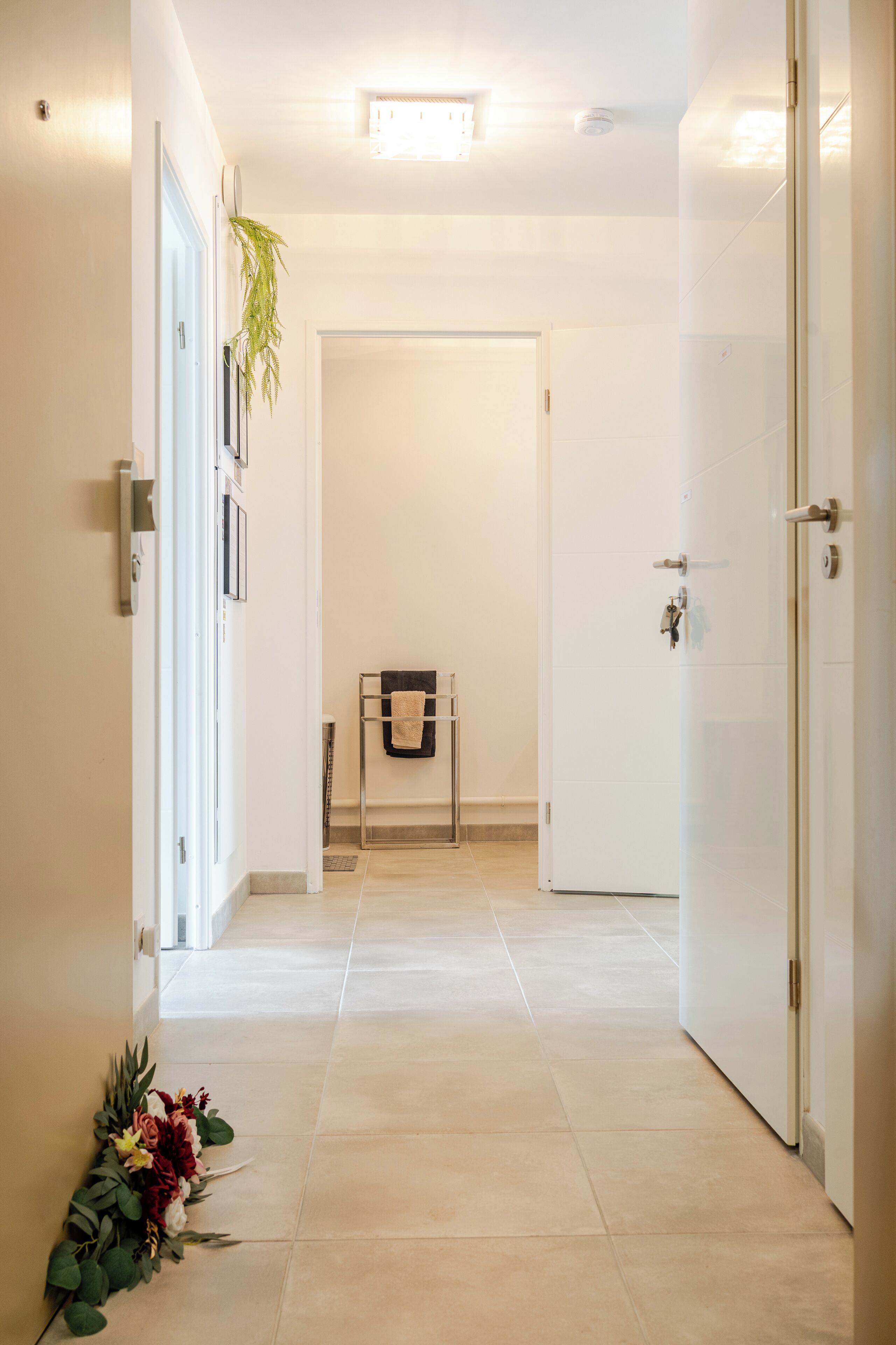 A hallway with a tiled floor, a door on the right, and a door at the end.