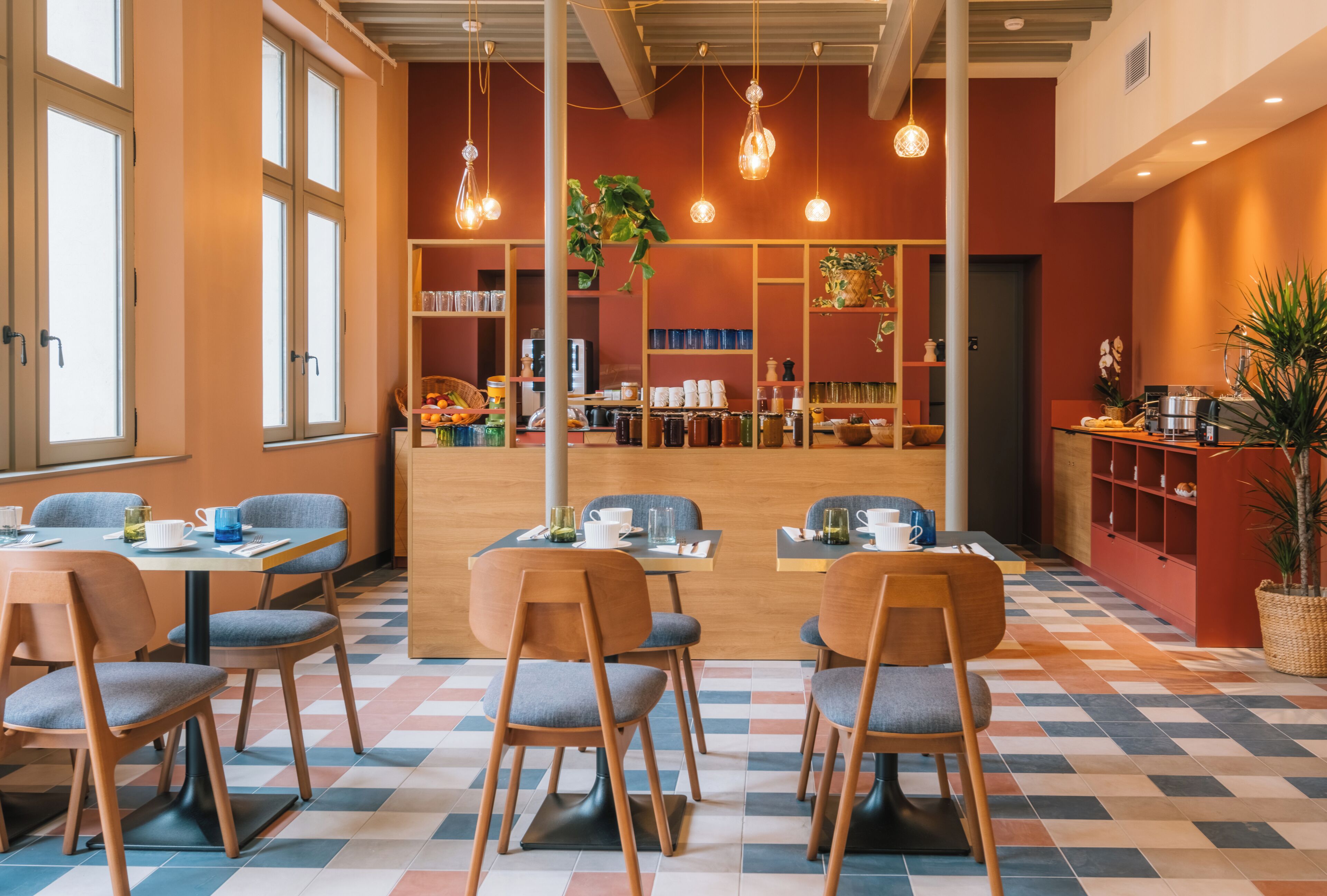 A modern cafe with wooden furniture, a checkered floor, and pendant lighting.