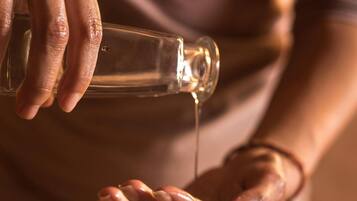 A person pouring a clear liquid from a bottle into their hands.