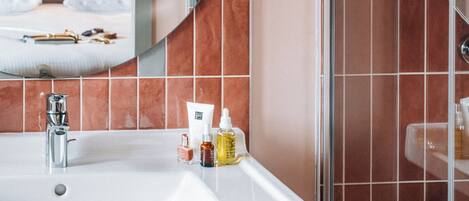 Une salle de bain avec un lavabo blanc, un miroir et un espace douche.