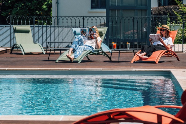 Een seizoensgebonden buitenzwembad, ligstoelen bij het zwembad