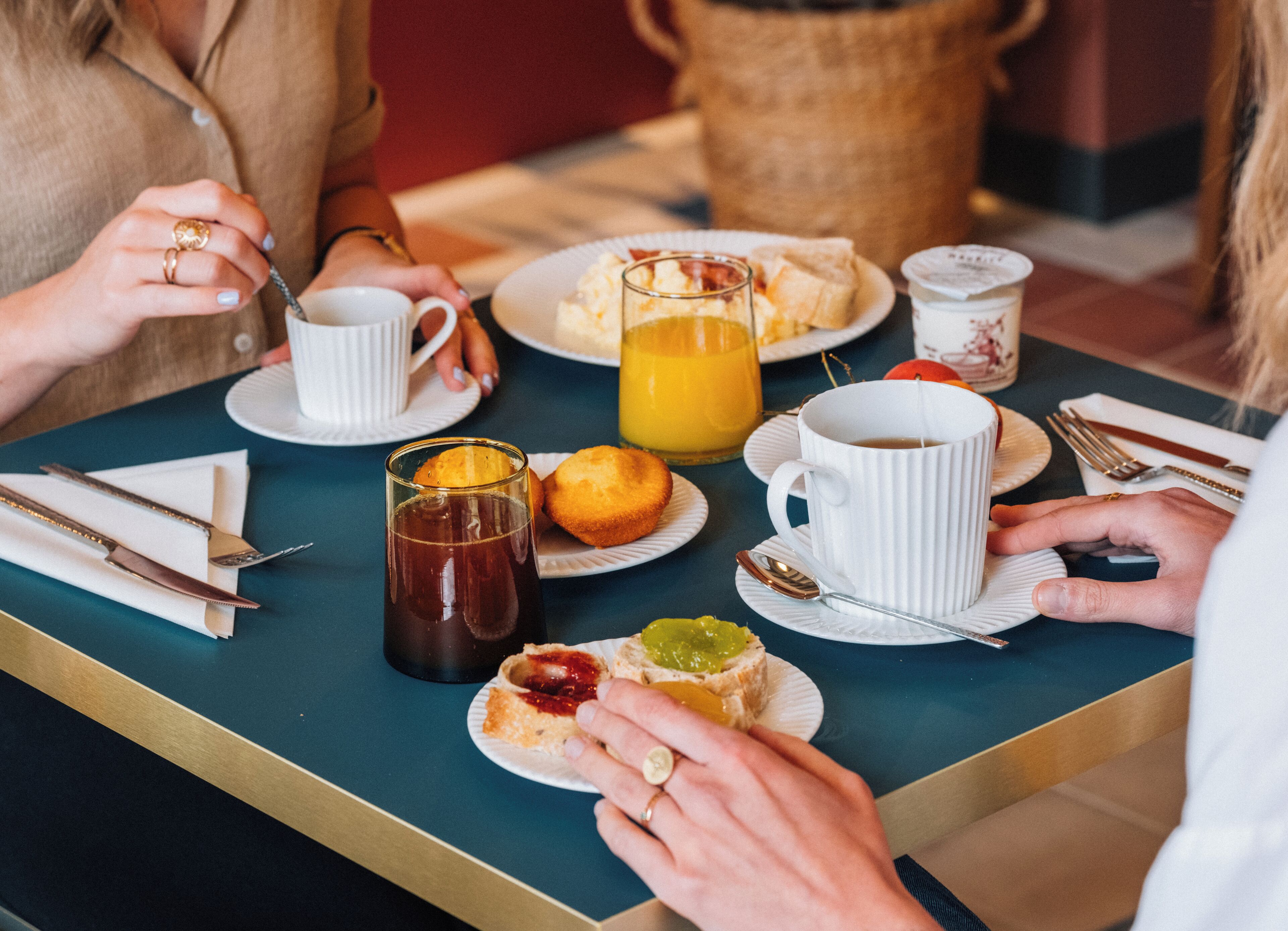 A breakfast table with plates of food, cups, and cutlery.