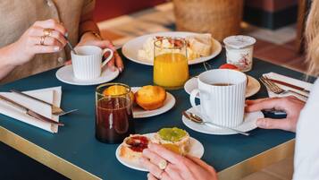 A breakfast table with plates of food, cups, and cutlery.