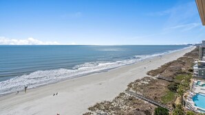 A beach with a long stretch of sand, a few people, and a building with a pool on the right. - 11th Floor Spacious Condo at Bahama Sands - 1103 (North Myrtle)