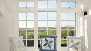 A window with a view of rolling hills and a clear sky. - Manor Cottage Barn (Callington)