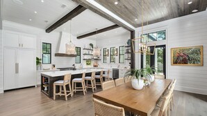 A spacious kitchen with white cabinetry, a wooden dining table, and a large island with seating. - Summer Nights|Easy Beach Access|Private PoolGolf Cart (Santa Rosa Beach)