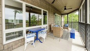 Eine überdachte Terrasse mit Korbmöbeln, einem blauen Tisch und Deckenventilatoren.