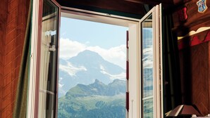 A bedroom with a large window offering a mountain view. - Drei Berge Hotel (Mürren)