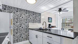 A modern kitchen with white cabinets, a black countertop, and a patterned backsplash. - Southern Daze I Walk to Jacob's Well & Morrow Park (Wimberley)