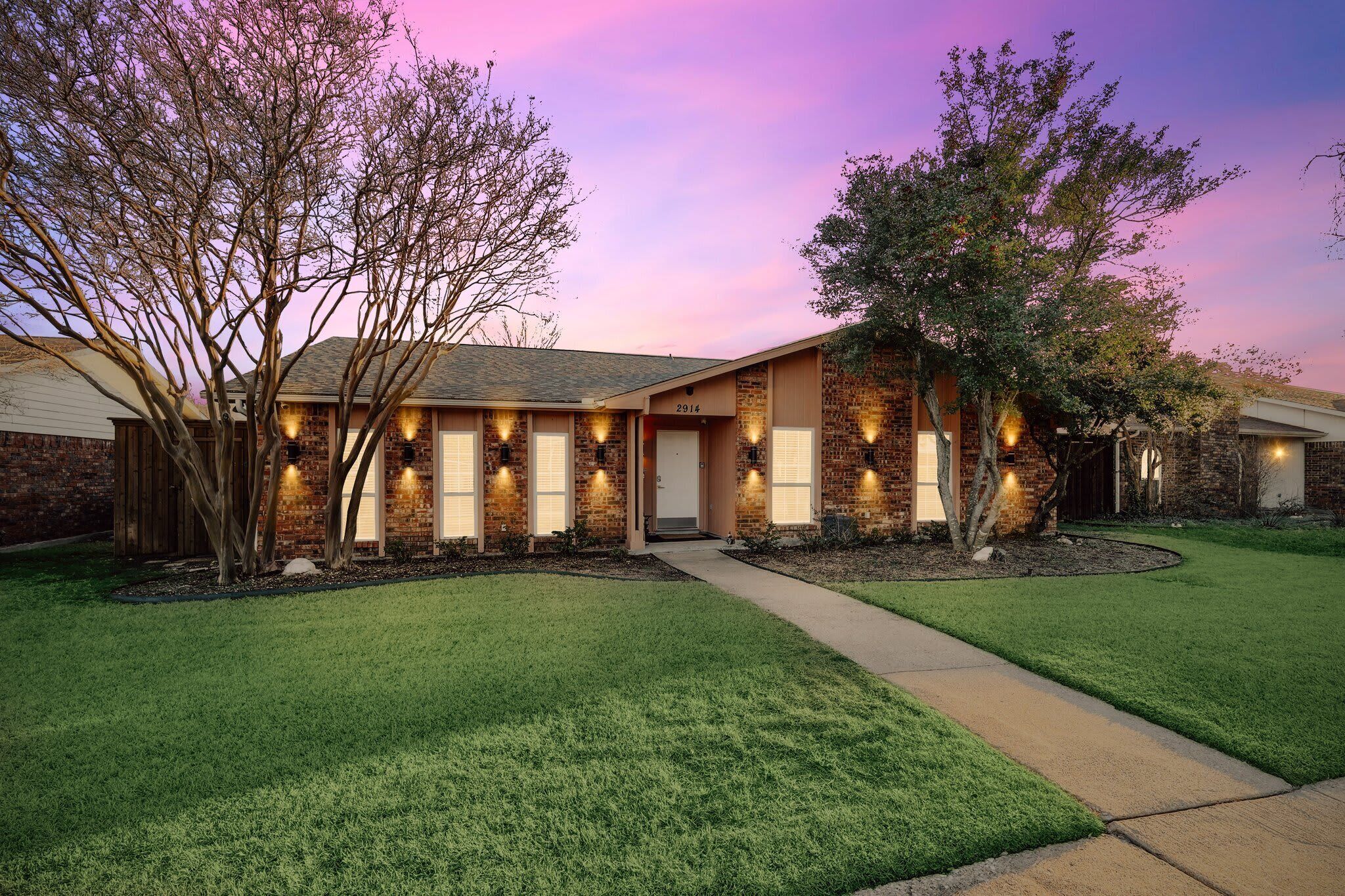 A two-story house with a brick facade, a front porch, and a well-maintained lawn.