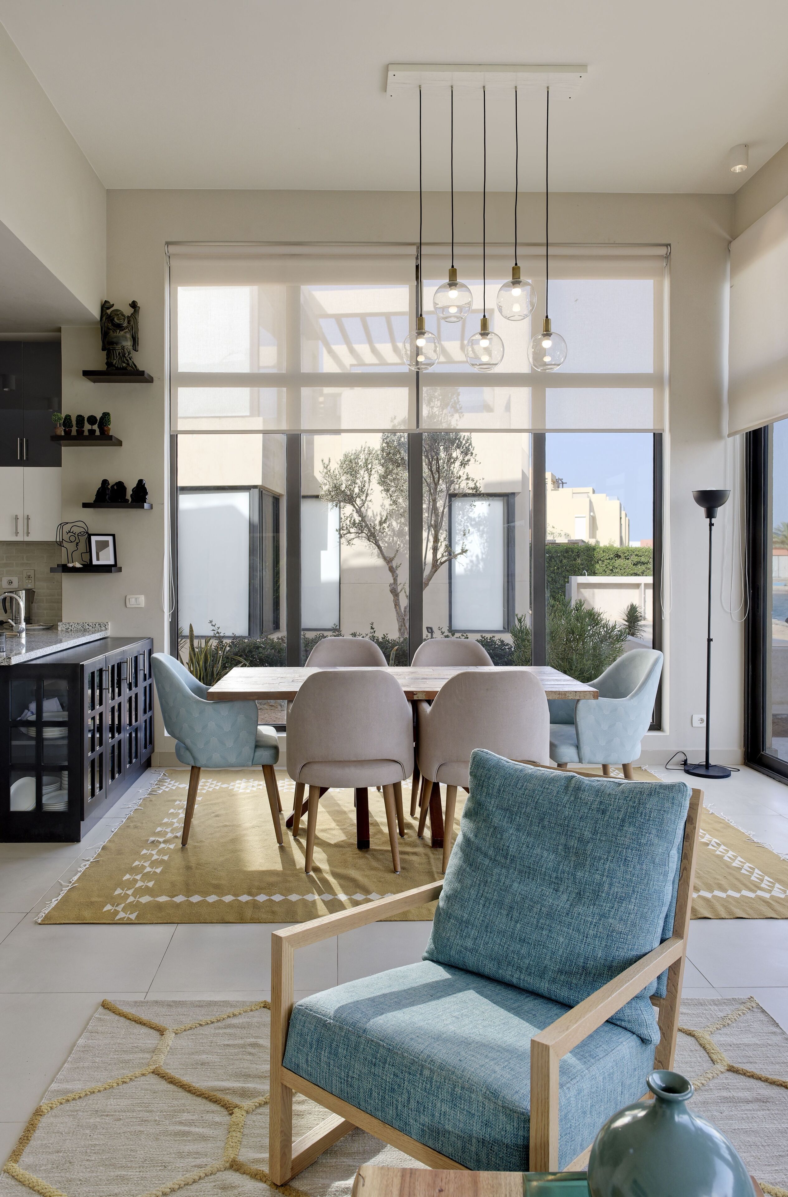 A modern dining area with a large window, a chandelier, and a view of the outside.