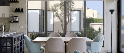 A modern dining area with a large window, a chandelier, and a view of the outside.