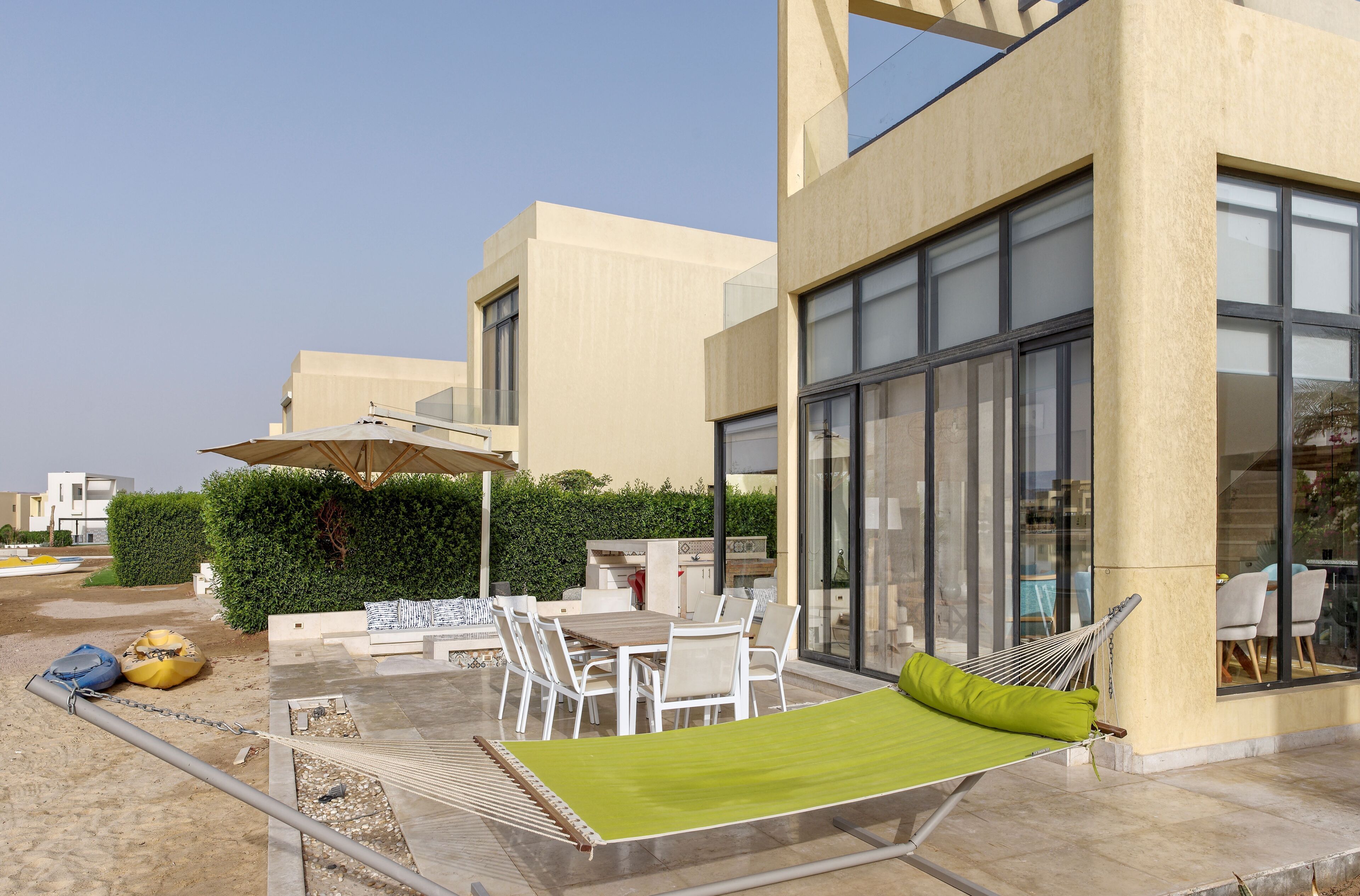 Eine moderne Außenpatio mit Esstisch, Stühlen und einer Hängematte.