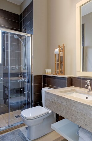 A modern bathroom with a glass-enclosed shower, a white toilet, a sink with a marble countertop, and a mirror above the sink. - Vesta - El Gouna Residence (El Gouna)
