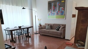 A living room with a dining table, chairs, a sofa, a lamp, and a painting on the wall. - House St. Peter Rome (Roma)