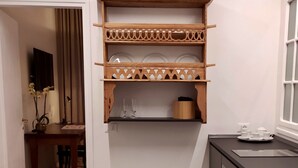 A compact kitchen with a wooden shelf above the countertop, a dining area with a table and chairs, and a small window. - House St. Peter Rome (Roma)