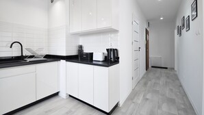 Een moderne keuken met witte kastjes, een zwart aanrecht en een koffiezetapparaat.