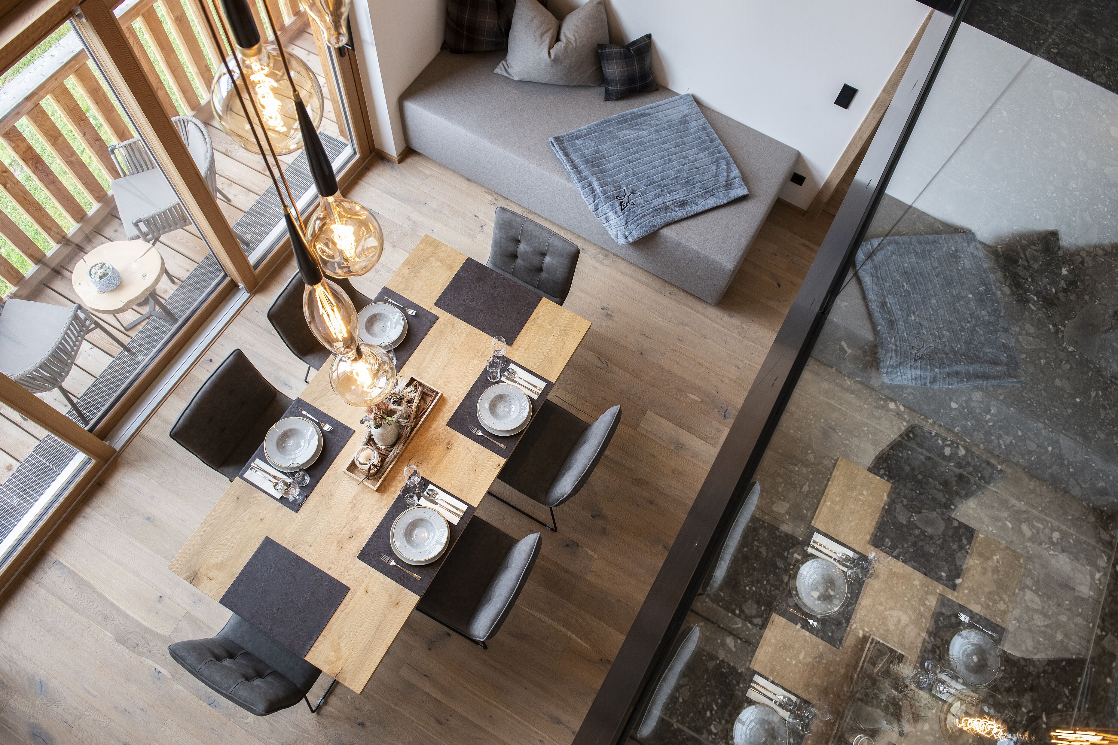 Un coin repas avec une table en bois, des chaises noires et grises, et un canapé gris en arrière-plan.