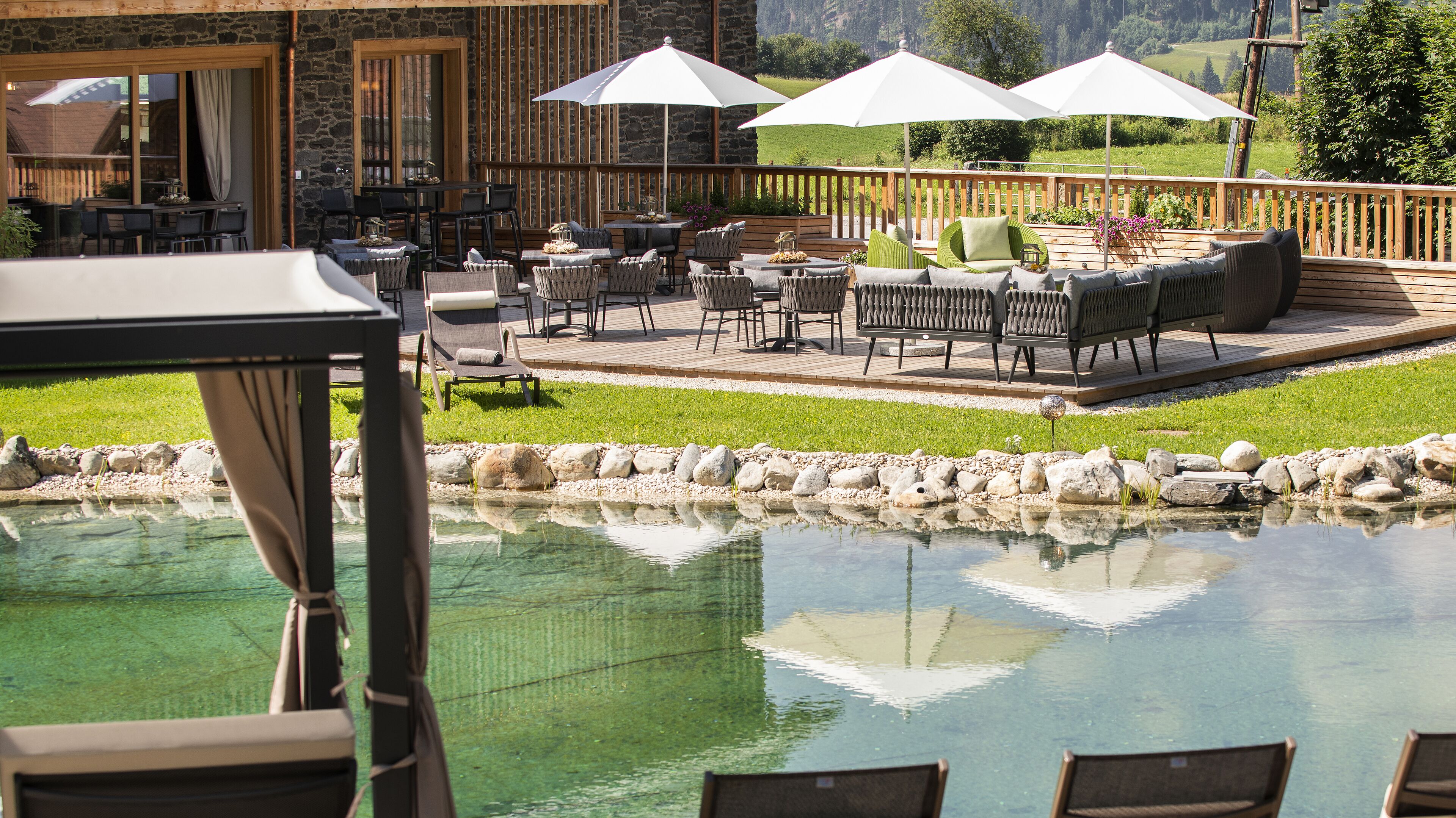 Une terrasse extérieure avec des tables et des chaises, une piscine et une vue sur le paysage environnant.