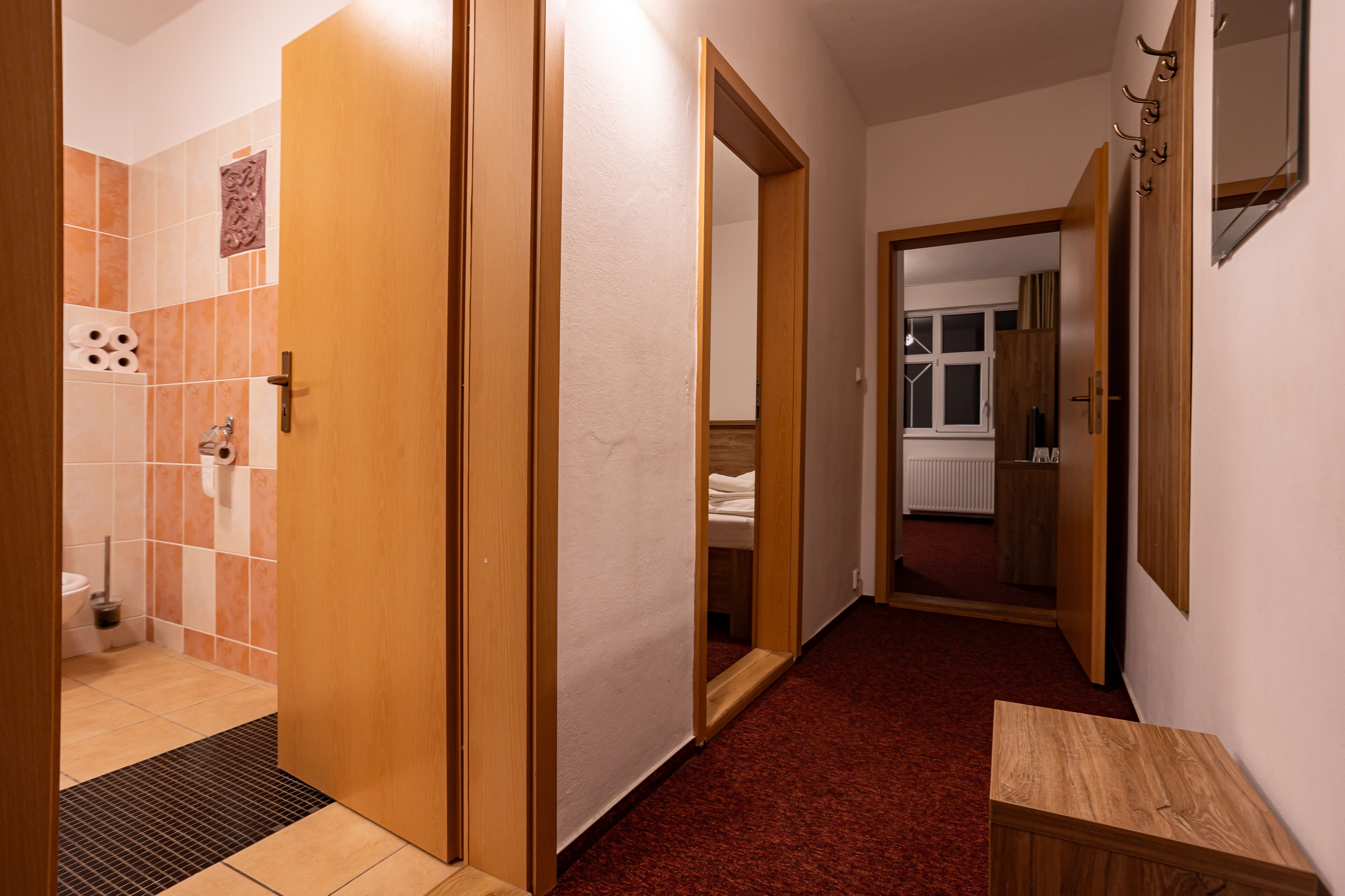 A hallway with a wooden door, a mirror, and a small wooden table.