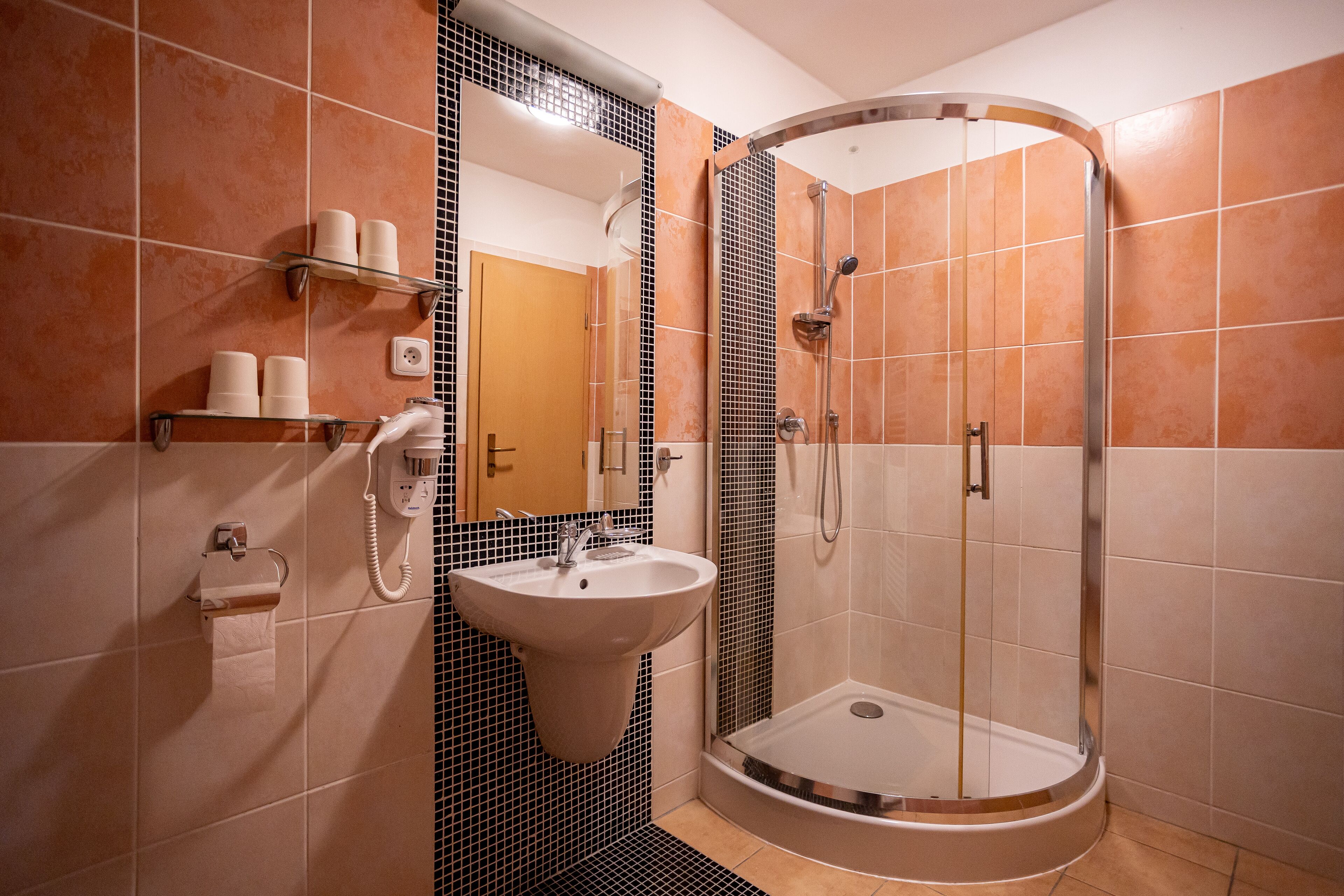 Un baño moderno con cabina de ducha curva, un lavamanos y un espejo.