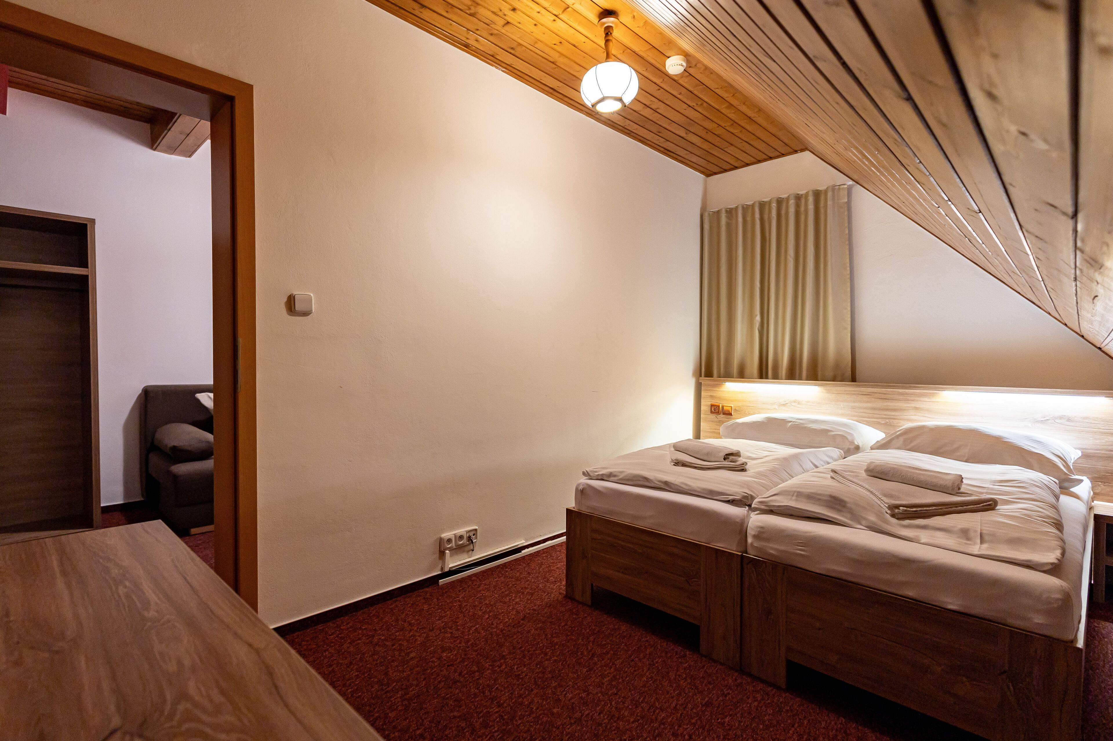 Ein Hotelzimmer mit Holzboden, einem Bett mit weißer Bettwäsche, einem Nachttisch aus Holz und einem kleinen Tisch.