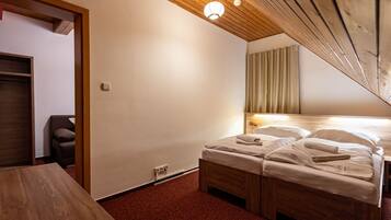 Ein Hotelzimmer mit Holzboden, einem Bett mit weißer Bettwäsche, einem Nachttisch aus Holz und einem kleinen Tisch.