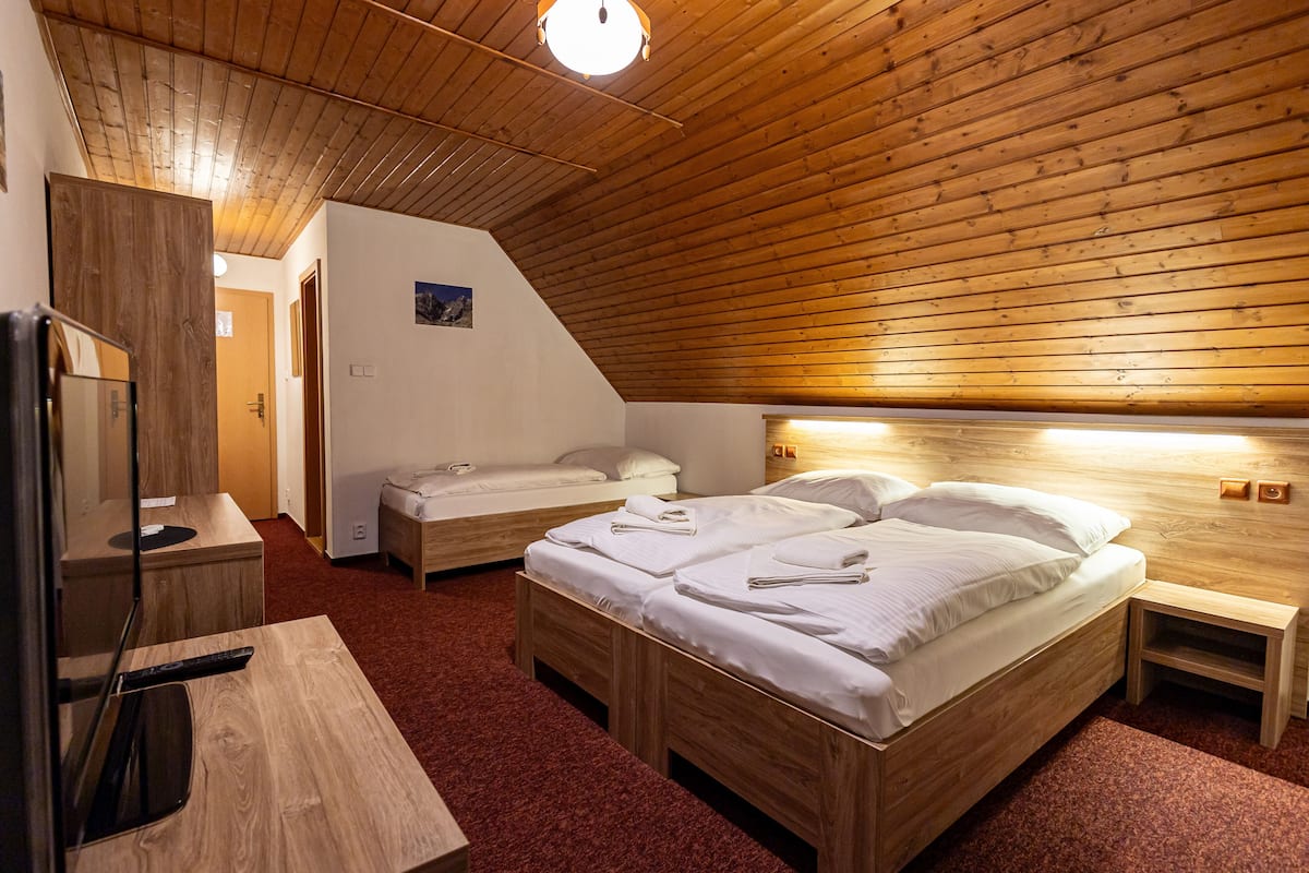 A room with two wooden beds, a wooden desk, and a mirror.