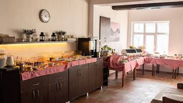 A kitchen with a buffet setup, including a refrigerator, stove, and various food items on the counter.