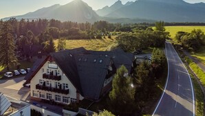 A two-story building with a sloped roof, a balcony on the second floor, and a sign that reads "LONNICKY". - Penzión Lomnicky (Stara Lesna)